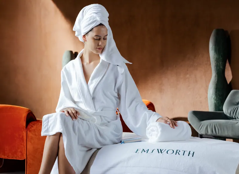 Guest in an Emsworth bathrobe beside a branded cushion